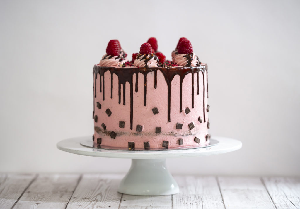 dark chocolate and raspberry occasion cake with fresh raspberries and chocolate drip effect