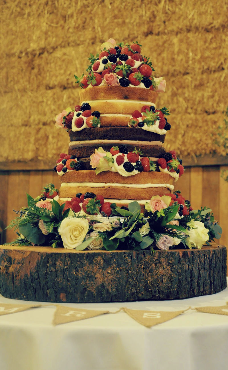 A three tier naked wedding cake at Pangdean Barn with fresh flowers