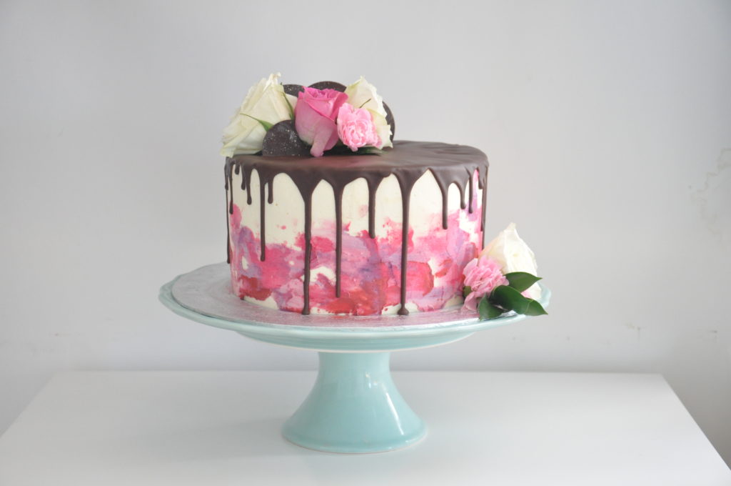 Buttercream cake with chocolate drip effect and fresh roses on top