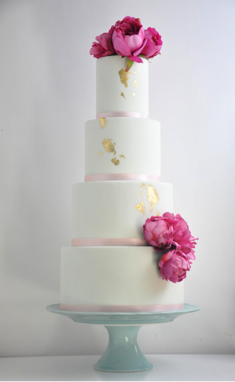 mint green and pink peonies on a four tier wedding cake with edible gold leaf