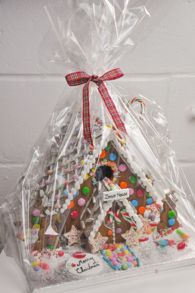 warpped extra large gingerbread house in cellophane with a red tartan ribbon