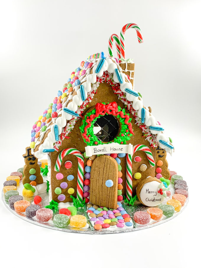 a very colourful gingebread house with candy canes on the front
