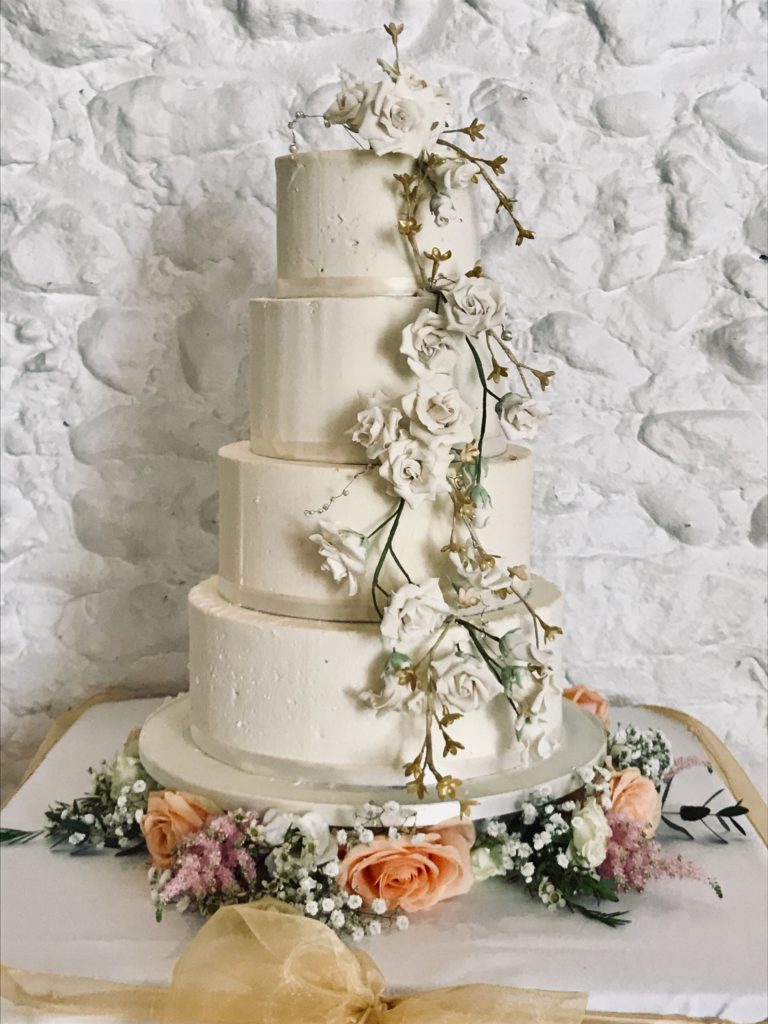 White buttercream wedding cake with sugar roses cascading down the front