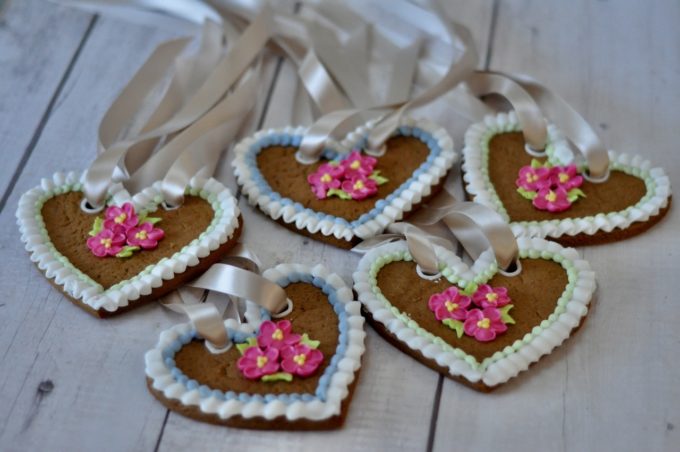 lebkuchen heart biscuist deocrated with royal icing pink roses and ribbons